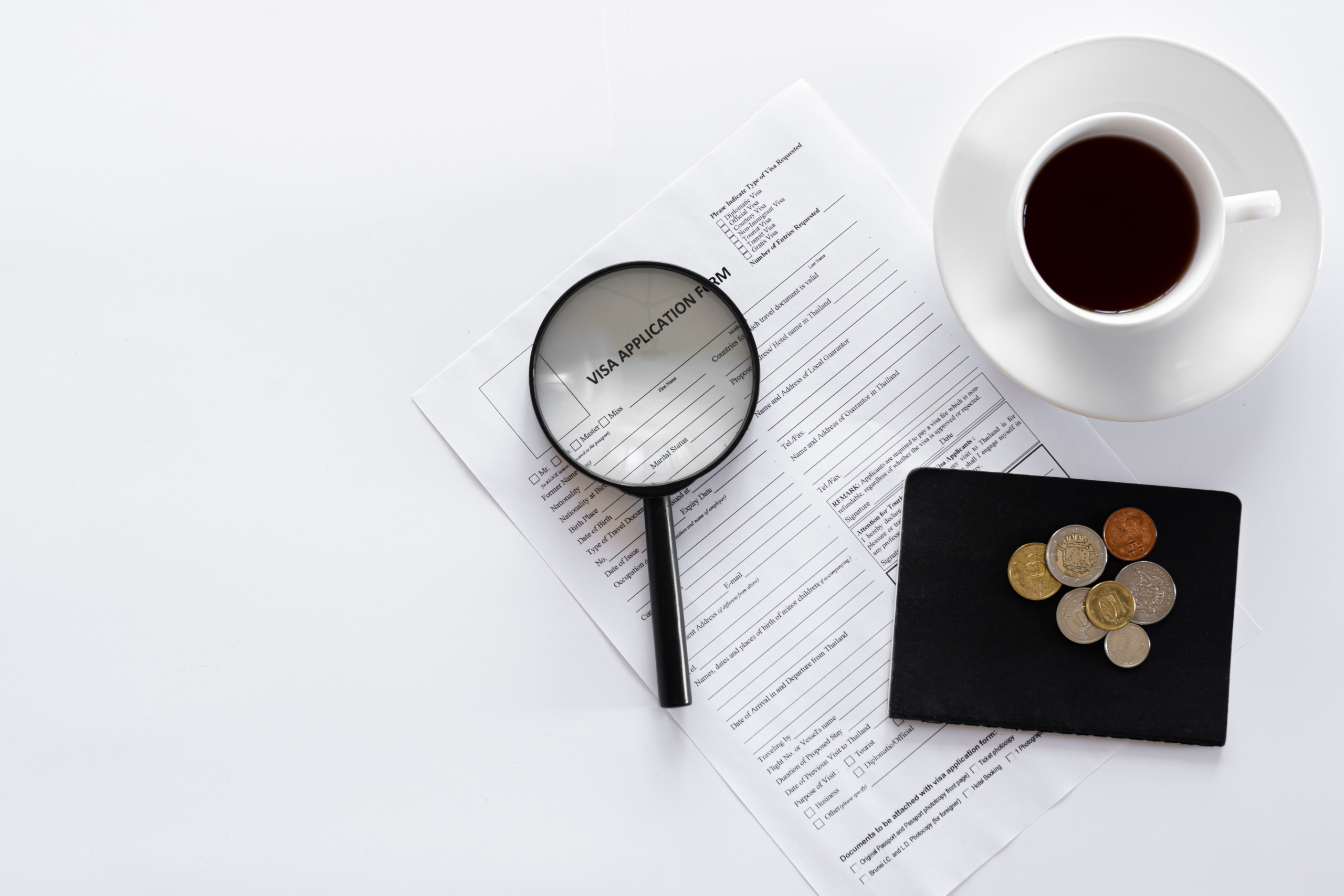 Visa application form, documents and a cup of coffee on a white background. tax investigation service cover